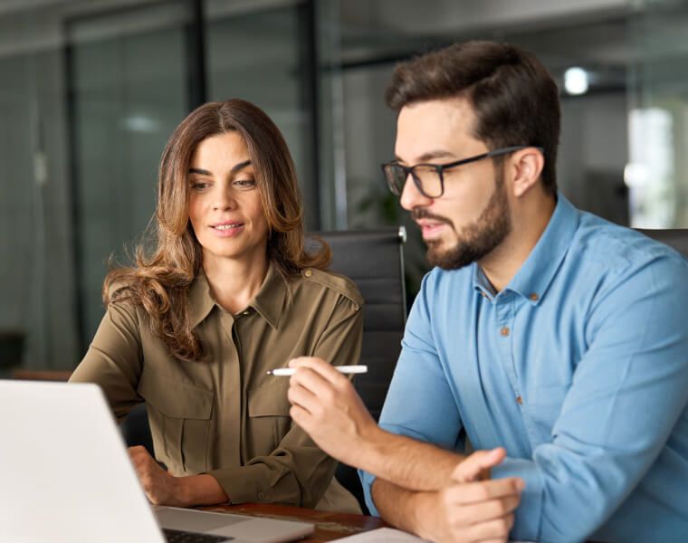 Two insurance professionals collaborating at a laptop in a modern office, reviewing AI-driven underwriting data – Neutrinos